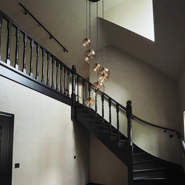 Treppenhaus mit Holztreppe und runden Hängeleuchten