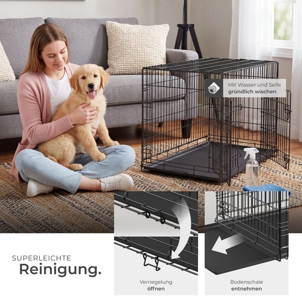 Schwarzer Hundekäfig aus Metall im Wohnzimmer mit Frau und Welpe, Detailansicht der herausnehmbaren Bodenschale für eine einfache Reinigung.