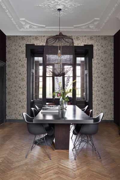 Helles Esszimmer mit Esstisch, Stühlen, Blumenvase, Pendelleuchte und gemusterter Tapete.