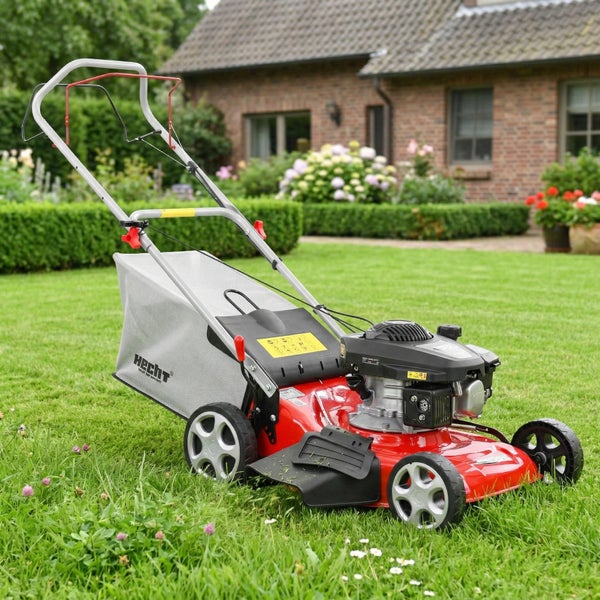 Benzin-Rasenmäher von Hecht mit Grasfangsack auf einer Rasenfläche vor einem Haus.