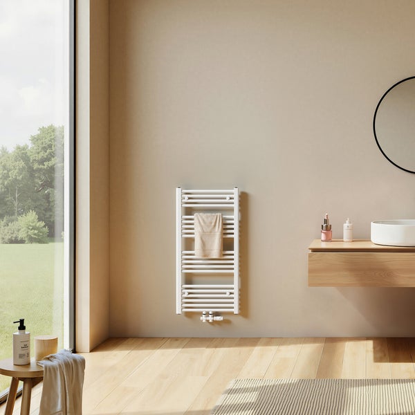 Moderner weißer Badheizkörper an einer beigen Wand in einem hellen Badezimmer mit Holzwaschtisch, rundem Spiegel und Fenster.