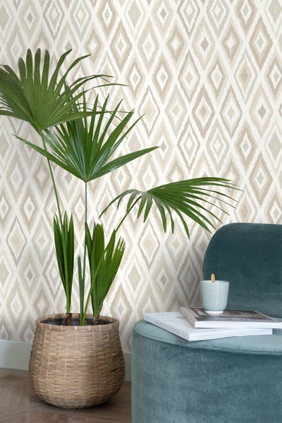 Dekoratives Wohnzimmer mit gemusterter Tapete, Zimmerpflanze im Korb und blauem Hocker.