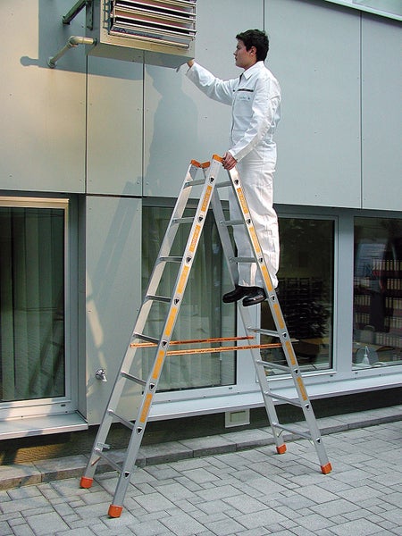 Mann auf einer Layher Stehleiter bei der Arbeit an einem Gebäude.