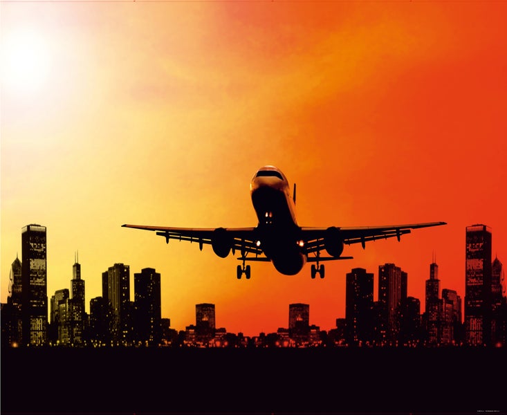 Flugzeug startet vor einer Stadtsilhouette bei Sonnenaufgang