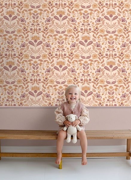 Mädchen mit Stofftier vor einer Wand mit Blumentapete