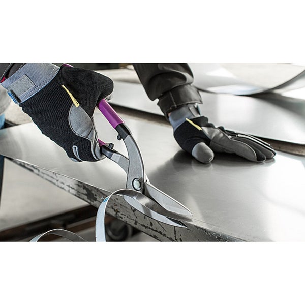 Eine Blechschere schneidet ein Metallblech in einer Werkstatt. Eine Person mit Arbeitshandschuhen führt das Werkzeug für einen präzisen Schnitt.