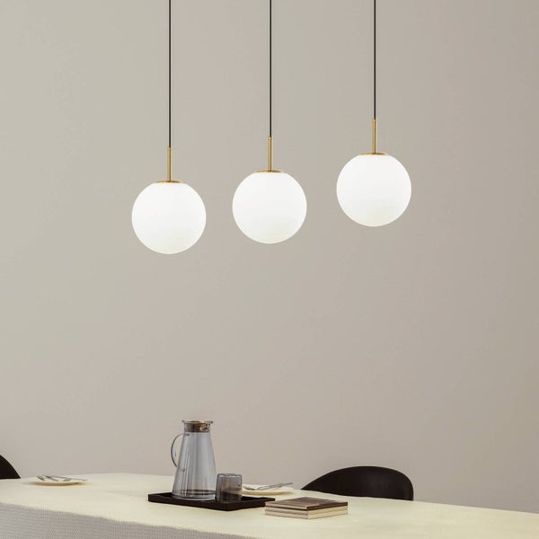 Dreiflammige Pendelleuchte mit weißen Glaskugeln und goldfarbenen Elementen über einem modern gedeckten Esstisch in einem hellen Raum.