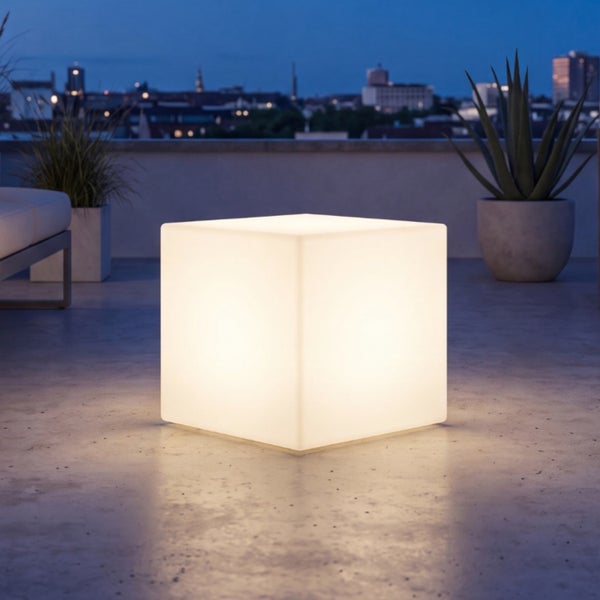 Beleuchteter LED Würfel als Außenleuchte oder Sitzhocker auf einer Terrasse bei Abenddämmerung mit Stadtblick.