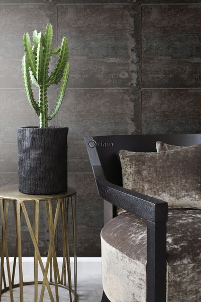 Dekoratives Interieur mit Kaktus in einem Topf auf einem Beistelltisch und einem Sessel im Hintergrund.