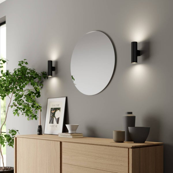 Wohnraum mit Kommode, rundem Spiegel und zwei Wandleuchten