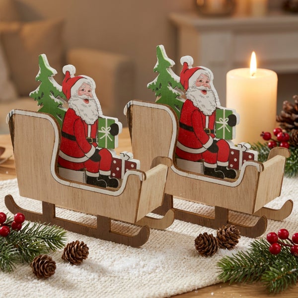 Zwei dekorative Holzschlitten mit Weihnachtsmann Figur, Tannenbaum und Geschenken als Tischdekoration für die Weihnachtszeit