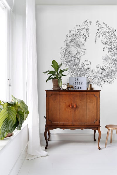Helles Zimmer mit Holzkommode, Zimmerpflanzen und floralem Wandtattoo