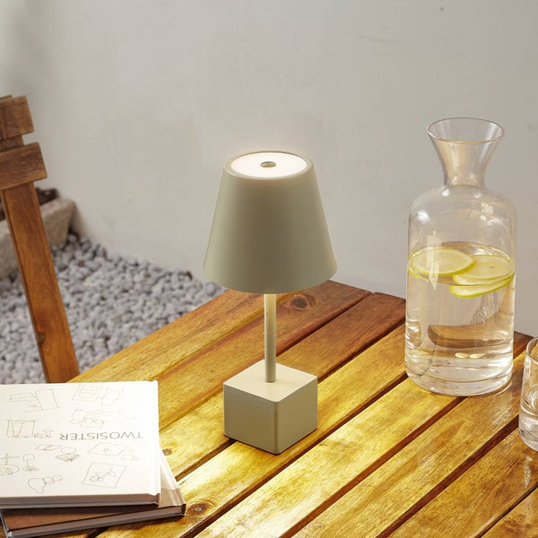 Moderne, kabellose LED-Tischleuchte für den Außenbereich auf einem Holztisch platziert, neben einer Glaskaraffe mit Zitronenwasser.