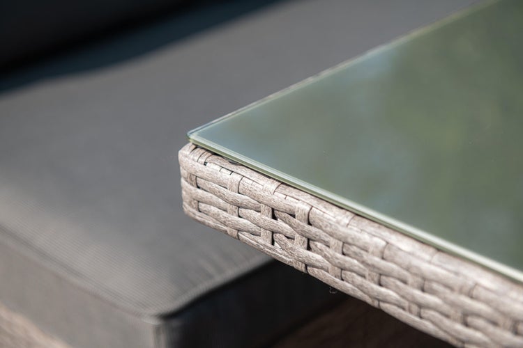 Detailansicht einer Ecke eines Garten-Beistelltischs mit Glasplatte und Polyrattan-Geflecht.