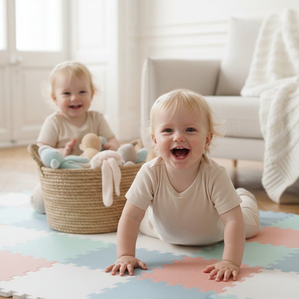Zwei lachende Kleinkinder auf einer bunten Schaumstoff-Spielmatte in einem hellen, organisierten Zimmer.