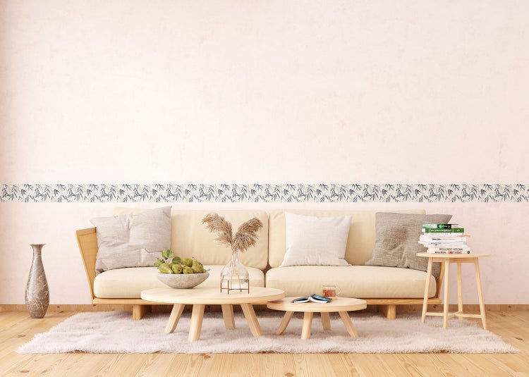 Helles Wohnzimmer mit hellem Sofa, Couchtischen aus Holz und einer horizontalen Tapetenbordüre mit Bambusblattmuster.