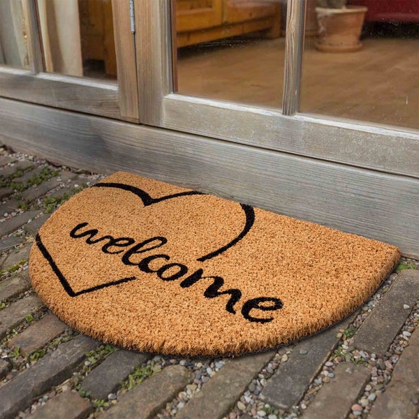 Fußmatte mit der Aufschrift "Welcome" und Herzmotiv vor einer Tür