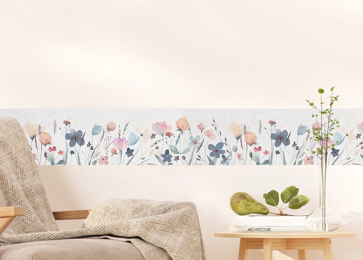 Tapetenbordüre mit Blumenmuster an der Wand in einem hellen, minimalistischen Wohnraum mit Sessel und kleinem Beistelltisch.