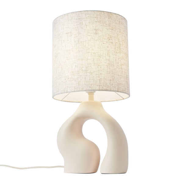 Tischleuchte mit organisch geformtem Keramikfuß und Textilschirm aus Stoff in Leinenoptik.