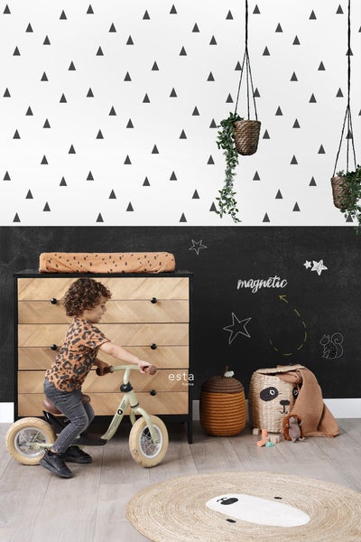 Kinderzimmer mit Kind auf Laufrad, Kommode, Spielzeug und Zimmerpflanzen in Hängekörben.