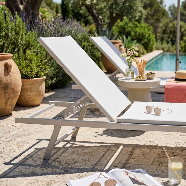 Verstellbare Gartenliege aus Metall mit Textilbespannung auf einer Steinterrasse neben einem Pool.