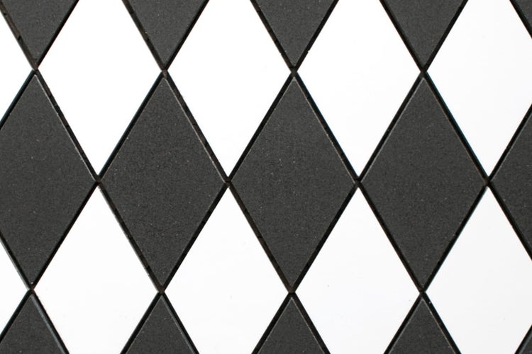 Mosaikfliesen in Rautenform, Harlekin-Muster, schwarz und weiß.