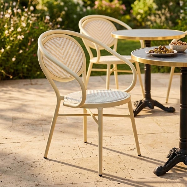 Bistro-Gartenstühle aus Metall mit gewebtem Fischgrätmuster und Rundtische auf einer sonnigen Terrasse im Garten.