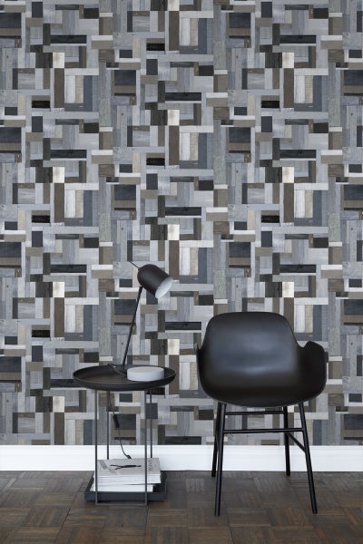 Wohnraum mit einer Wandtapete im Holzdesign, einem schwarzen Stuhl und einem Beistelltisch mit Lampe