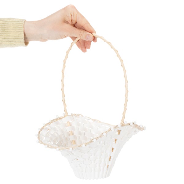 Hand hält einen kleinen geflochtenen Dekokorb mit hohem Henkel und gewelltem Rand.