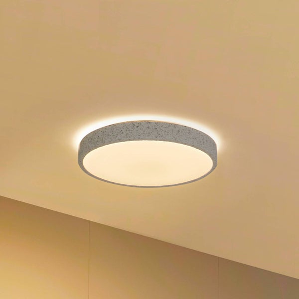 Runde LED Deckenleuchte mit strukturiertem Rahmen in Steinoptik, eingeschaltet mit warmweißem Licht an einer Decke montiert.