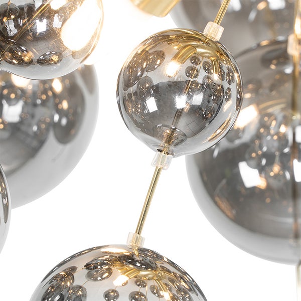 Nahaufnahme einer Hängeleuchte mit mehreren runden Glasschirmen und goldenen Stäben