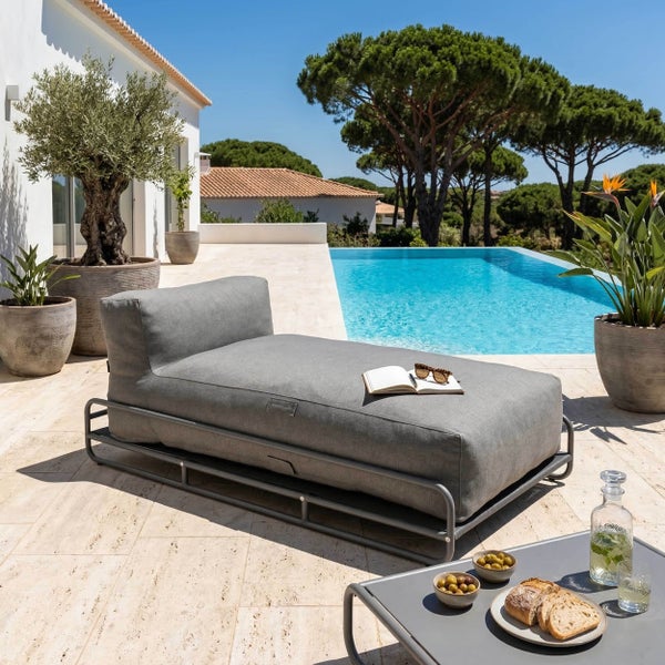 Modernes graues Outdoor-Daybed mit dickem Polster auf Metallgestell, auf einer Steinterrasse neben einem Pool im Aussenbereich.