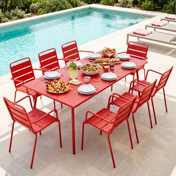 Rotes Gartenmöbel-Set aus Metall mit großem Esstisch und acht Stühlen auf einer hellen Terrasse neben einem Swimmingpool.
