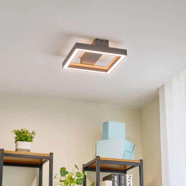 Moderne quadratische LED Deckenleuchte mit dunkelgrauem Rahmen und warmweißem Licht an einer weißen Zimmerdecke montiert.