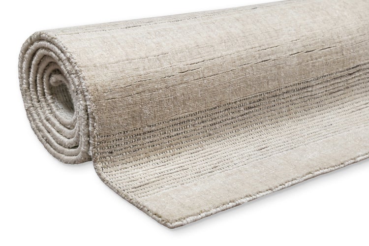 Rechteckiger Teppich mit feinem Streifenmuster vor einem hellen Sofa mit verschiedenen Dekokissen in einem modern gestalteten Wohnzimmer.