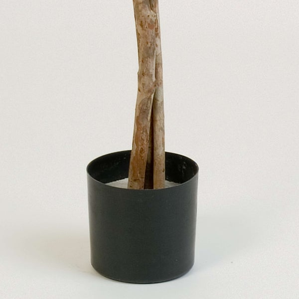 Künstliche Palme mit hohem Stamm und grünen Wedeln in einem schwarzen Kunststofftopf.