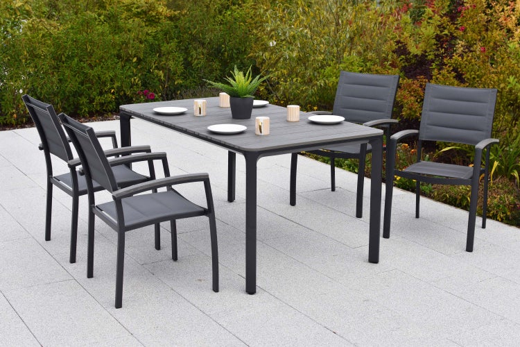 Gartentisch mit Stühlen auf einer Terrasse, dekoriert mit Tellern, Kerzen und einer Topfpflanze.