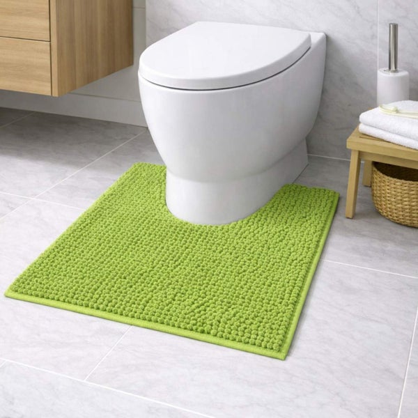 Hellgrüne, strukturierte Toilettenvorlage mit Ausschnitt vor einer weißen Toilette in einem hellen Badezimmer mit Fliesenboden und Holzmöbeln.