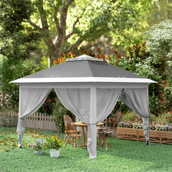 Quadratischer Gartenpavillon mit Textildach, Belüftungsöffnung und Vorhängen in einem hellen Garten mit Holzmöbeln auf dem Rasen.