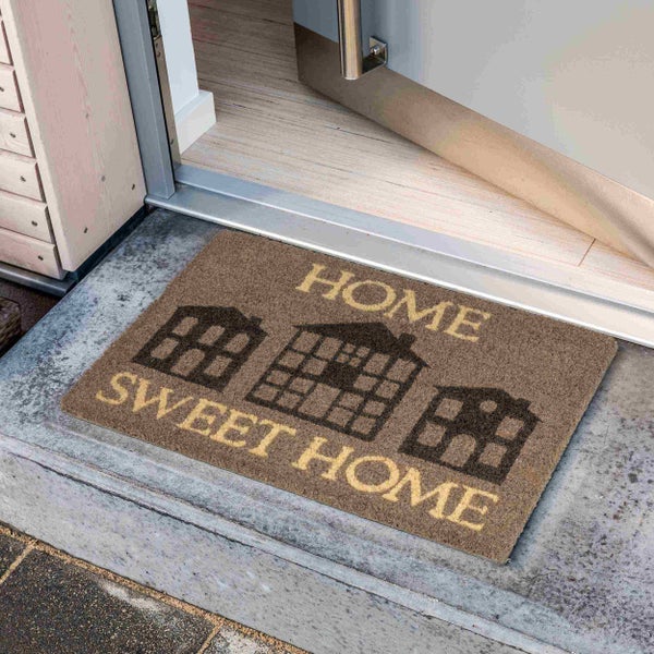 Fußmatte mit der Aufschrift Home Sweet Home und Häusern vor einer offenen Tür.