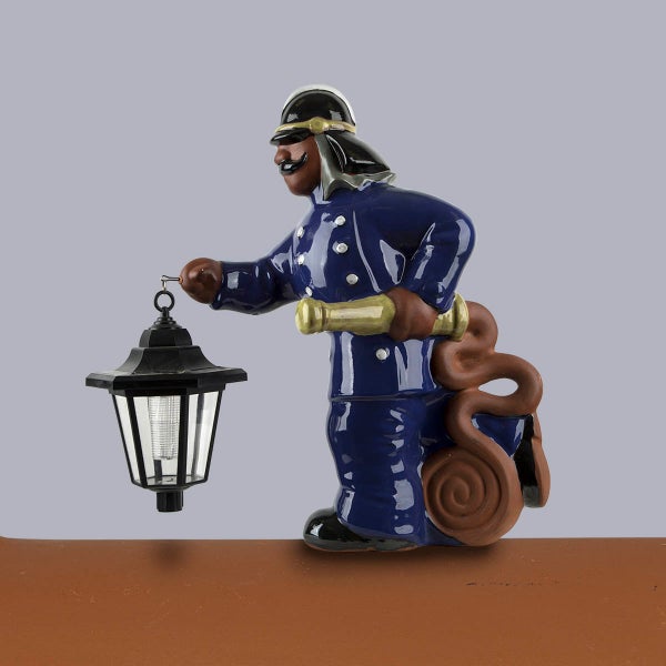 Gartenfigur Feuerwehrmann aus Keramik in blauer Uniform mit Solarlaterne und Strahlrohr.
