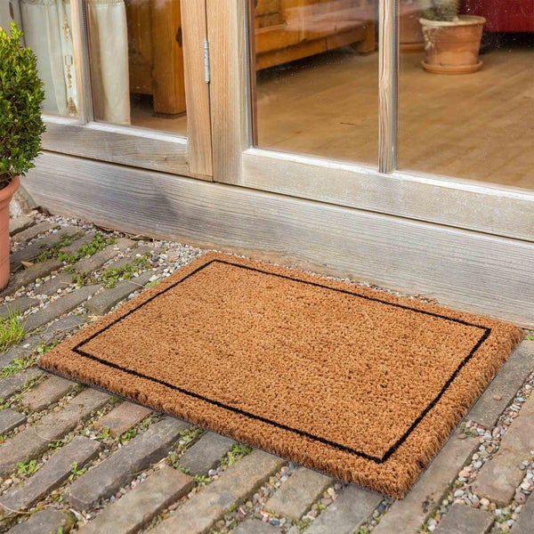 Fußmatte aus Kokosfaser mit rechteckigem Design und schwarzem Rand vor einer Haustür