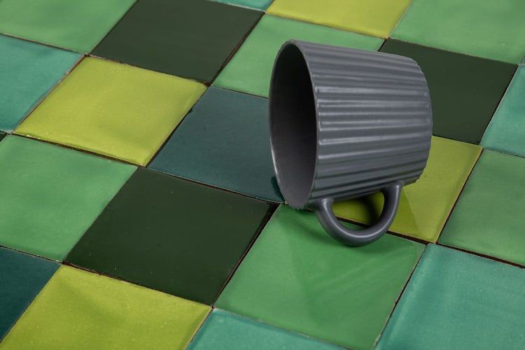 Fliesenmuster in verschiedenen Grüntönen mit einer grauen Tasse