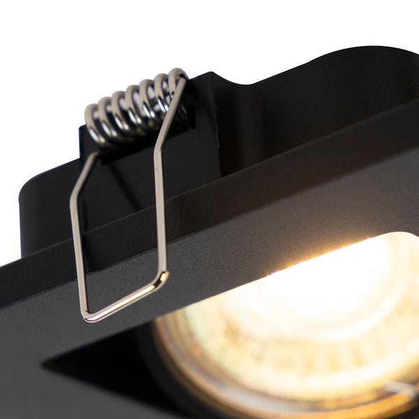 Nahaufnahme eines schwarzen LED-Einbaustrahlers mit Metall-Montagefeder und leuchtendem Leuchtmittel.