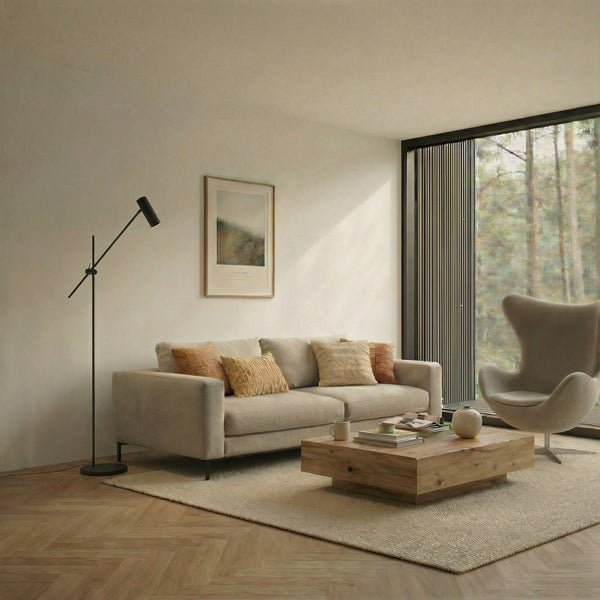 Wohnzimmer mit Sofa, Sessel, Couchtisch, Stehlampe und Fenster mit Blick in den Wald.