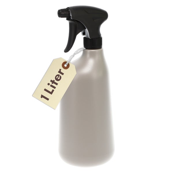 Eine Hand besprüht die Blätter und Luftwurzeln einer Monstera Zimmerpflanze mit Wasser aus einer Sprühflasche.