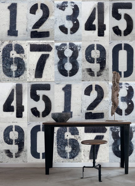 Dekorative Wand mit aufgemalten Ziffern, darauf Tisch und Stuhl
