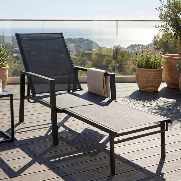 Moderne Gartenliege mit Metallgestell und Textilbespannung auf einer sonnigen Terrasse mit Meerblick.