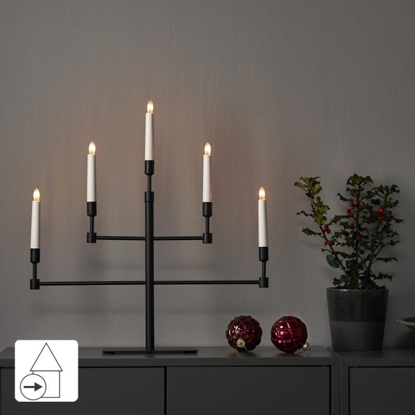 Dekoration mit dreifachem LED Kerzenleuchter und Weihnachtsschmuck auf einem Schrank