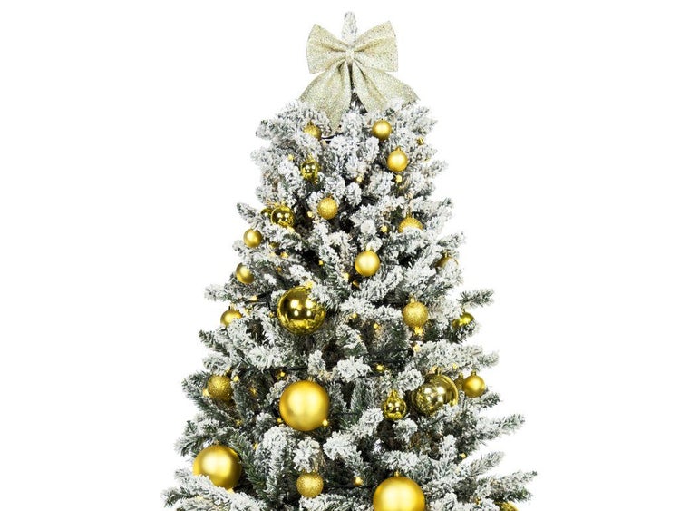 Künstlicher Weihnachtsbaum mit künstlichem Schnee und goldener Schleife als Baumspitze sowie goldfarbenen Weihnachtskugeln geschmückt.